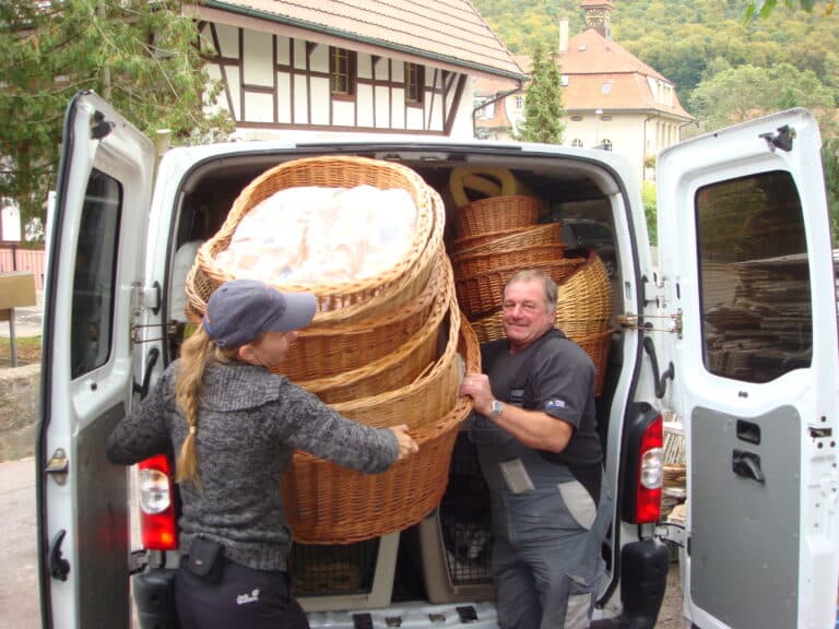 Eine Helferin und ein Helfer laden Hundekörbe in einen Lieferwagen