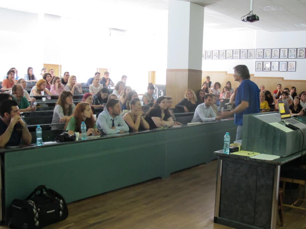 A lecture hall packed with veterinarians, with a speaker at the lectern in front.